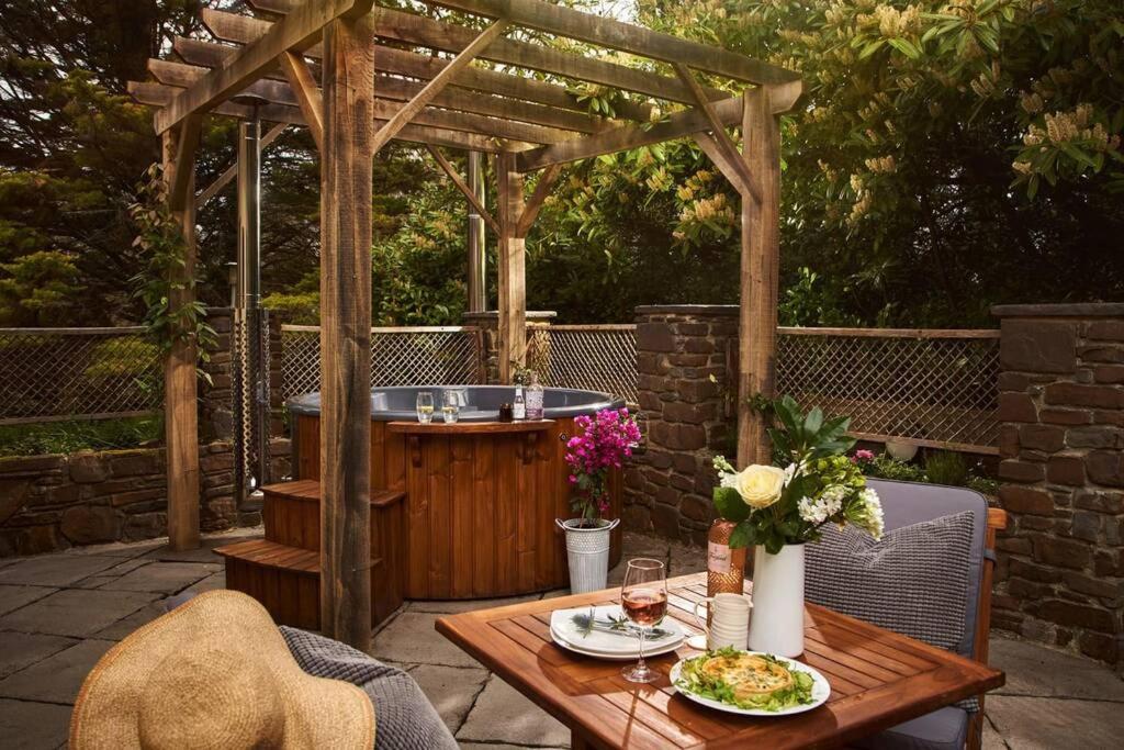 uma pérgola de madeira com uma banheira de hidromassagem e uma mesa em Swifts Return - Apartment with hot tub, sauna and indoor pool (Dartmoor) em Exeter