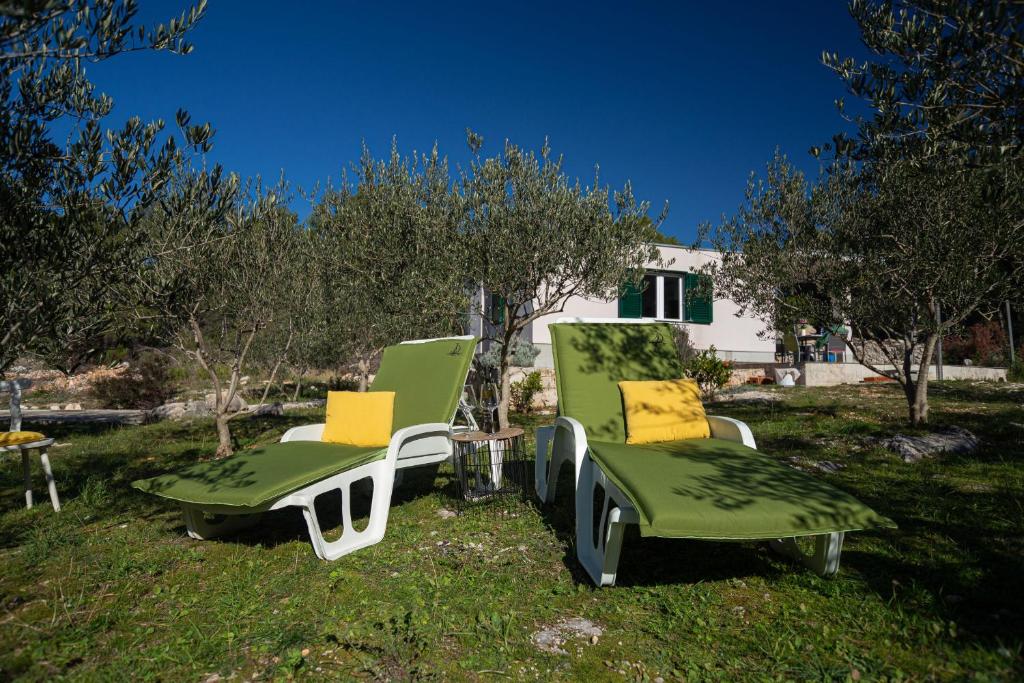 duas cadeiras verdes e brancas sentadas na relva em Olive Eden Holiday Home em Milna