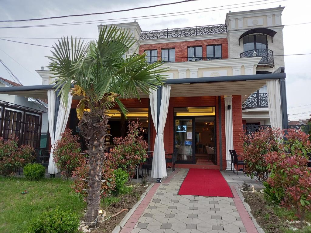 una casa con una palmera y una alfombra roja en Conti Hotel & Restaurant, en Gjakove