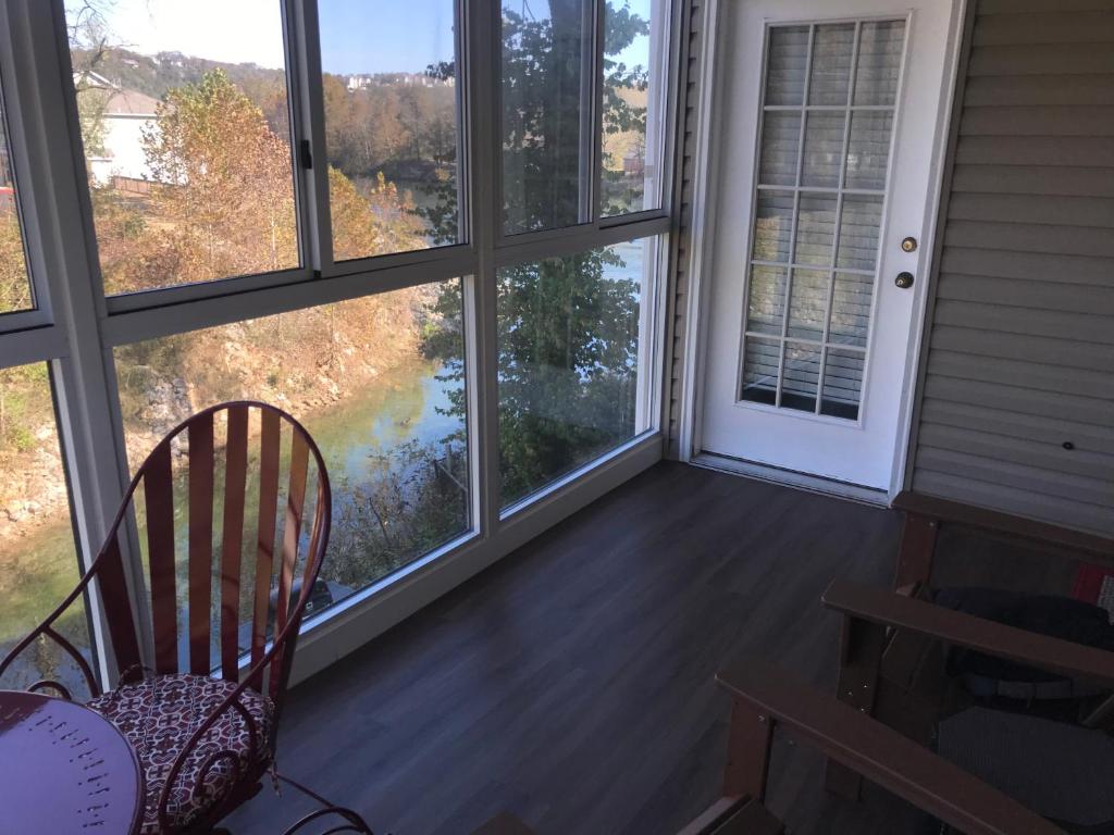a screened in porch with a chair and windows at Lakeside Condo on Lake Taneycomo in Branson