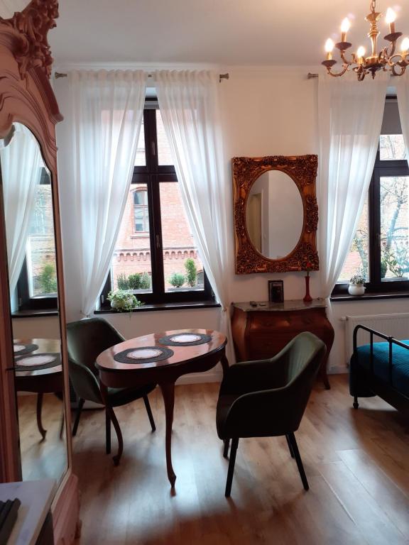 een woonkamer met een tafel en stoelen en een spiegel bij Apartment lux gimnazjalna in Bydgoszcz