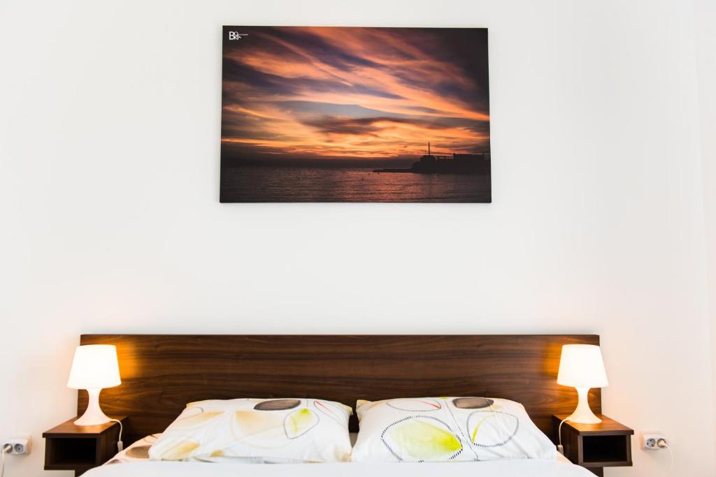 um quarto com uma cama com 2 candeeiros e um quadro em Apartment Adriatic Blue em Tivat