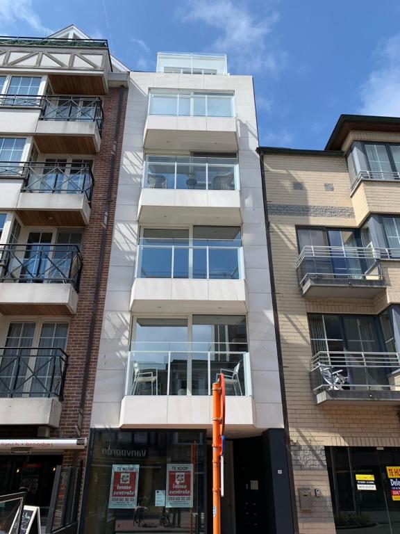 een appartementencomplex met een oranje paal ervoor bij Nieuwbouwappartement Lippenslaan, 2 -Slaapkamers in Knokke-Heist