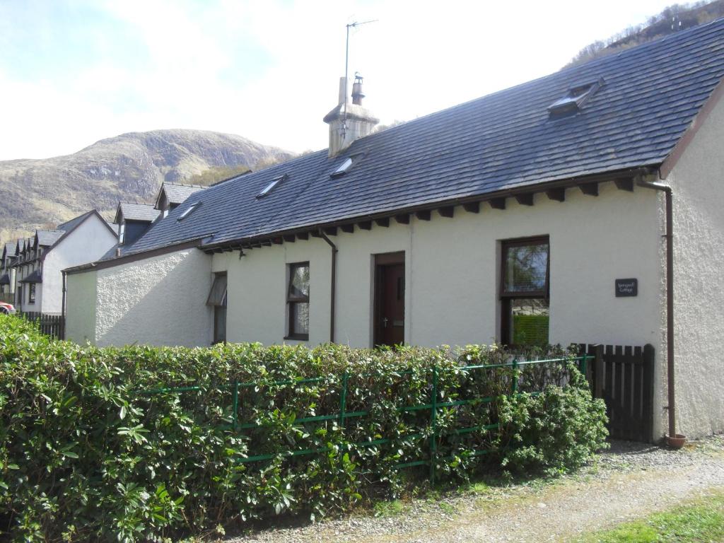 a white house with a black roof at Springwell Cottage in Fort William