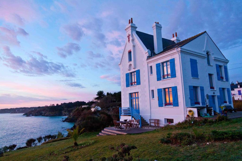 a large white house on a hill next to the water at Villa de Jade in Le Palais