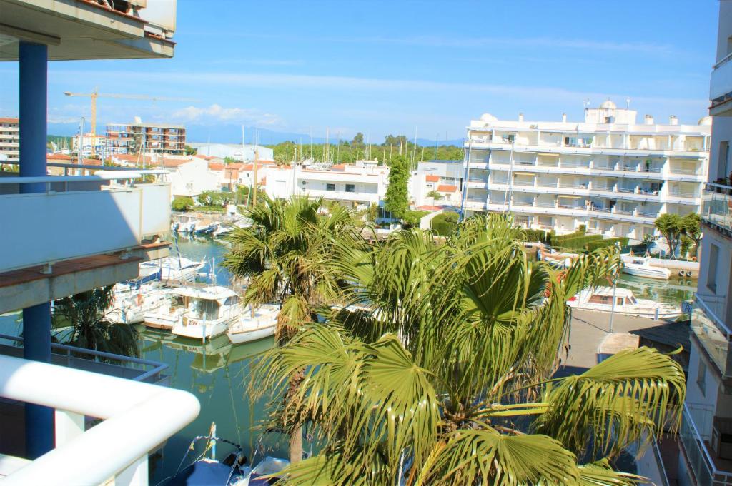 a view of a marina with palm trees and boats at Apartamento con vistas al canal en residencia con piscina in Roses