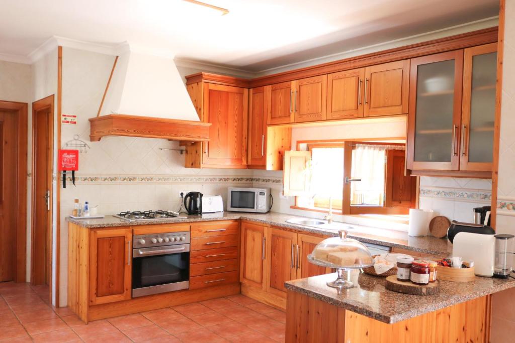 a kitchen with wooden cabinets and a stove top oven at Quinta Amarela - B&B in Nazaré
