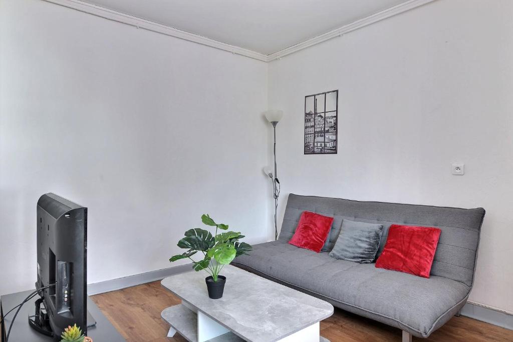 a living room with a gray couch and red pillows at Appartement 2 pièces plein de charmes - Caroline in Valentigney