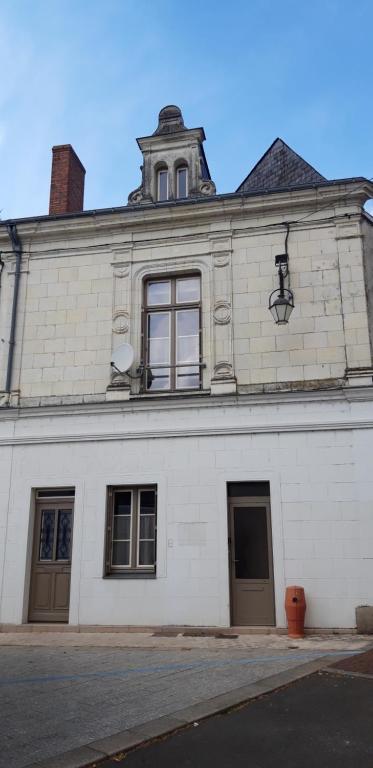 a white building with a clock tower on top of it at À 200m du Château 30 min du Circuit du Mans in Le Lude