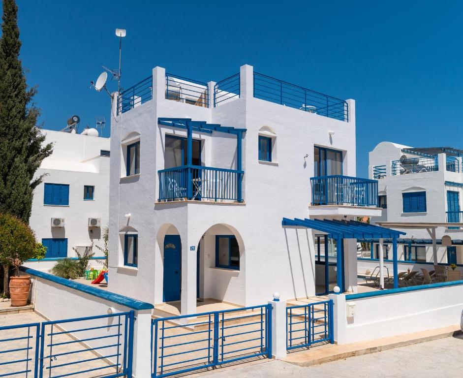 una casa blanca con una valla azul delante de ella en St Nicolaos Villa Ekaterina 3 bdrm, en Protaras