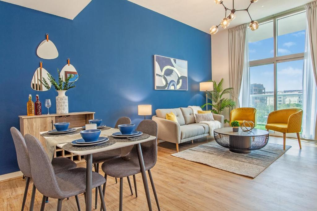a living room with blue walls and a table and chairs at Live Modern Live Luxury - Dubai Studio City in Dubai