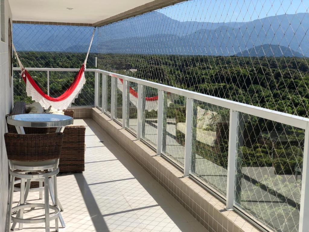 a balcony with a table and chairs and a view at Condominio Reserva da Mata - Riviera de São Lourenço in Riviera de São Lourenço