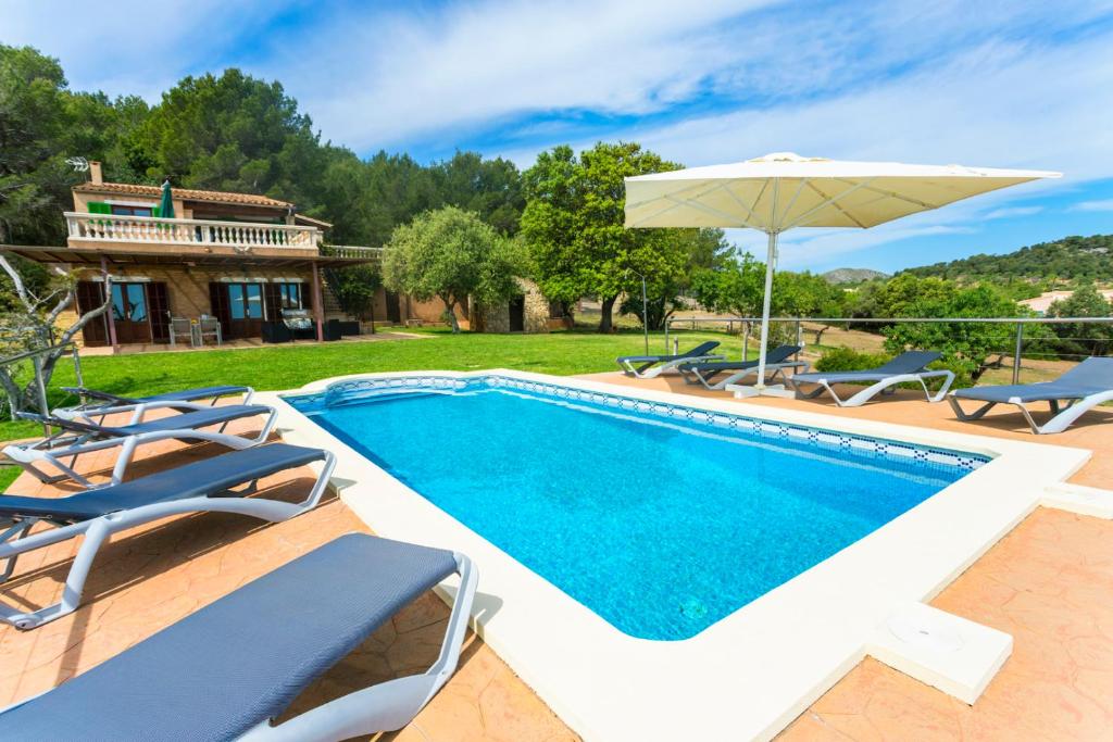 a swimming pool with chairs and an umbrella at Maricel in Cala Ratjada