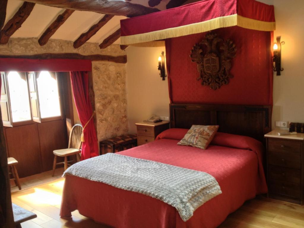 a bedroom with a bed with a red canopy at Hotel Rural El secreto del Castillo in Maderuelo