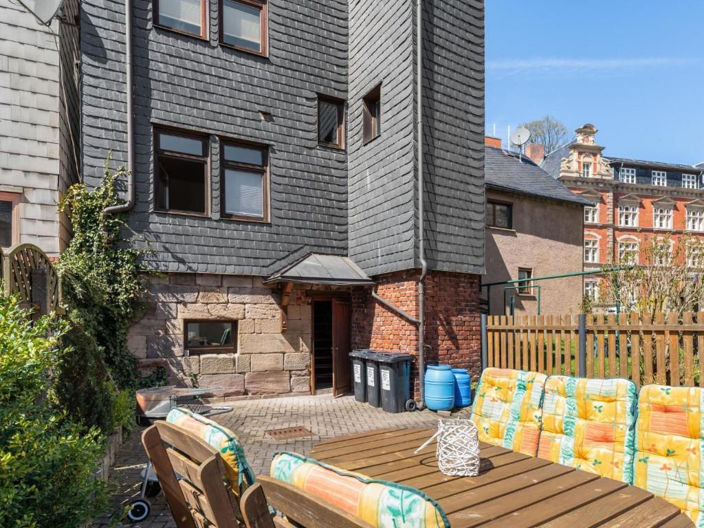 a patio with a wooden table and chairs in front of a house at Stylish apartment with terrace in Sonneberg in Sonneberg