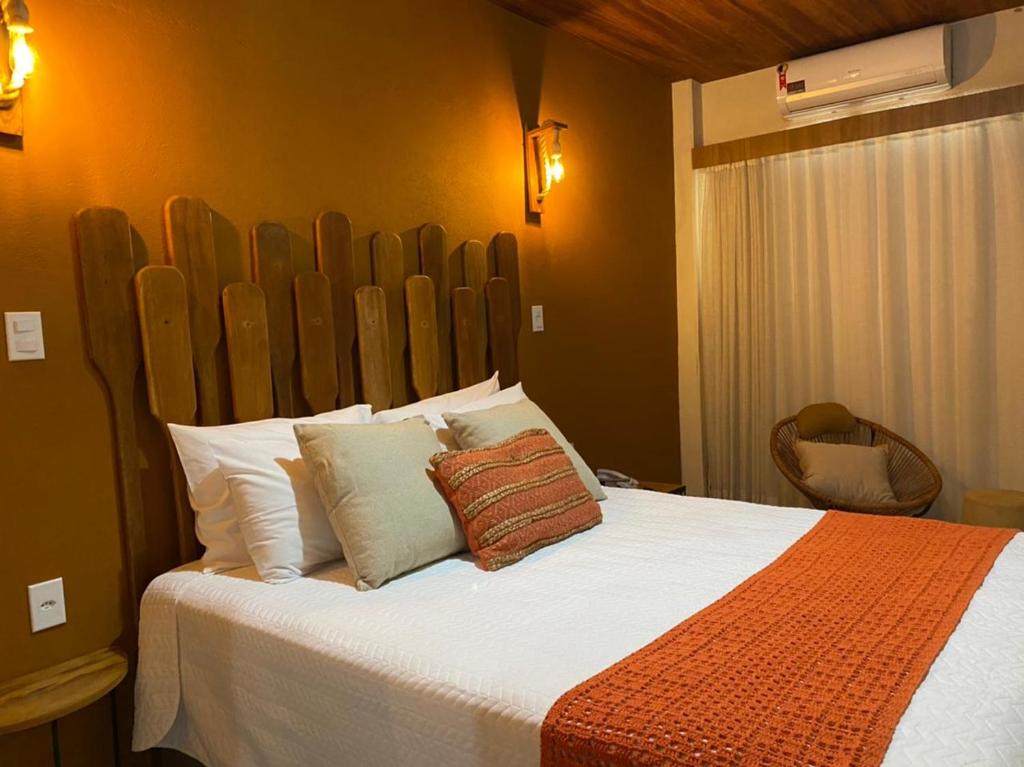 - une chambre avec un grand lit et une tête de lit en bois dans l'établissement Pousada Carapeba, à São Francisco