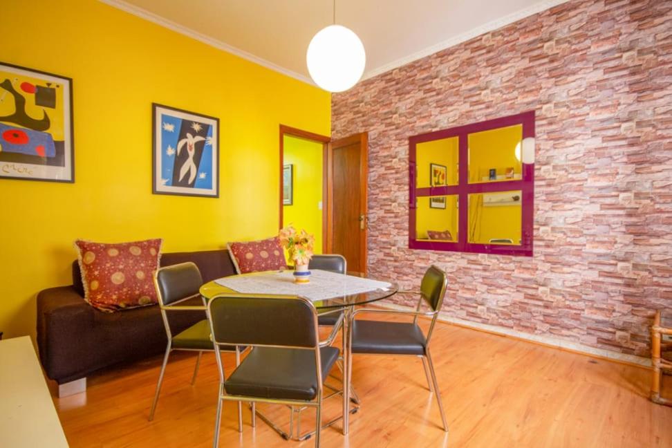 - un salon avec une table et des chaises ainsi qu'un mur en briques dans l'établissement Apartamento Arouche, à São Paulo