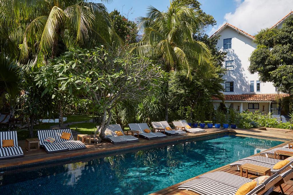 a swimming pool with trees and palm trees at Santa Teresa Hotel RJ - MGallery in Rio de Janeiro