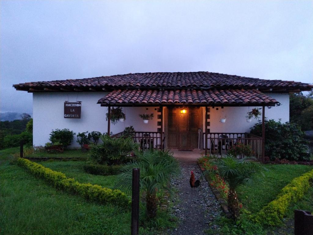 a small white house with a door in a yard at Hacienda Cafetera La Gaviota in Chinchiná