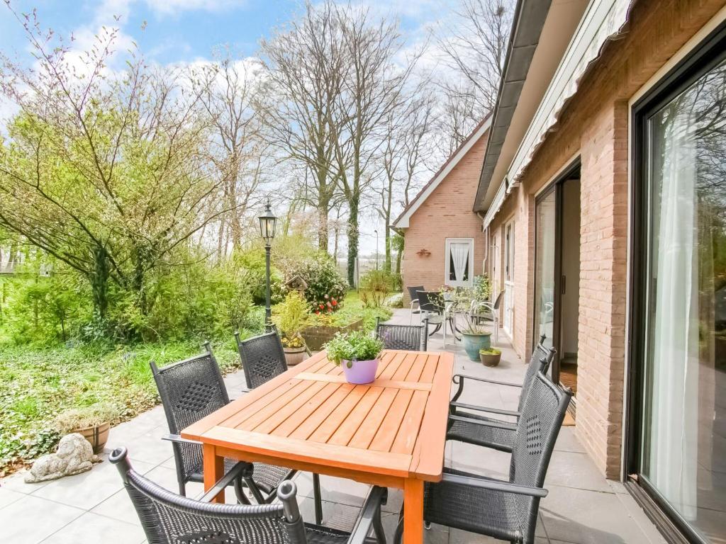 una mesa de madera y sillas en un patio en Holiday home near the Efteling with garden en Nieuwkuijk