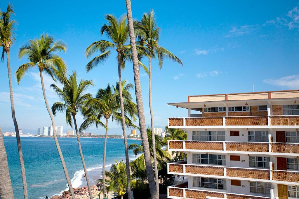 a beach with palm trees and palm trees at Hotel Rosita in Puerto Vallarta
