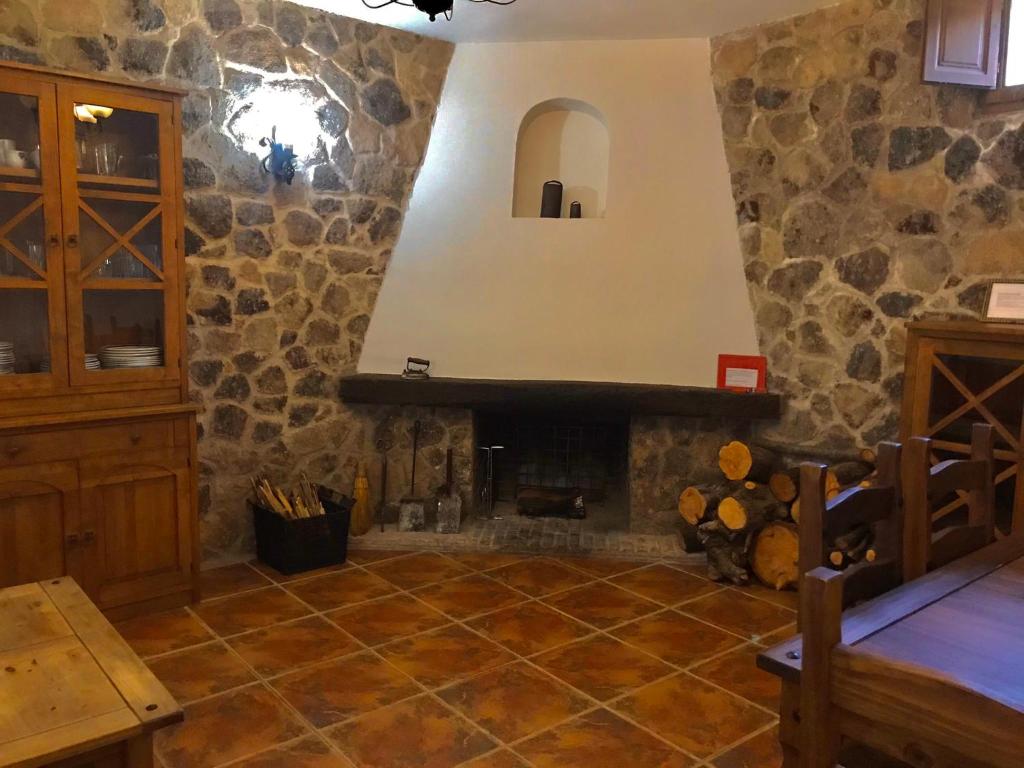 a living room with a stone fireplace in a house at CASA RURAL LA CABRERA in Casas del Castañar
