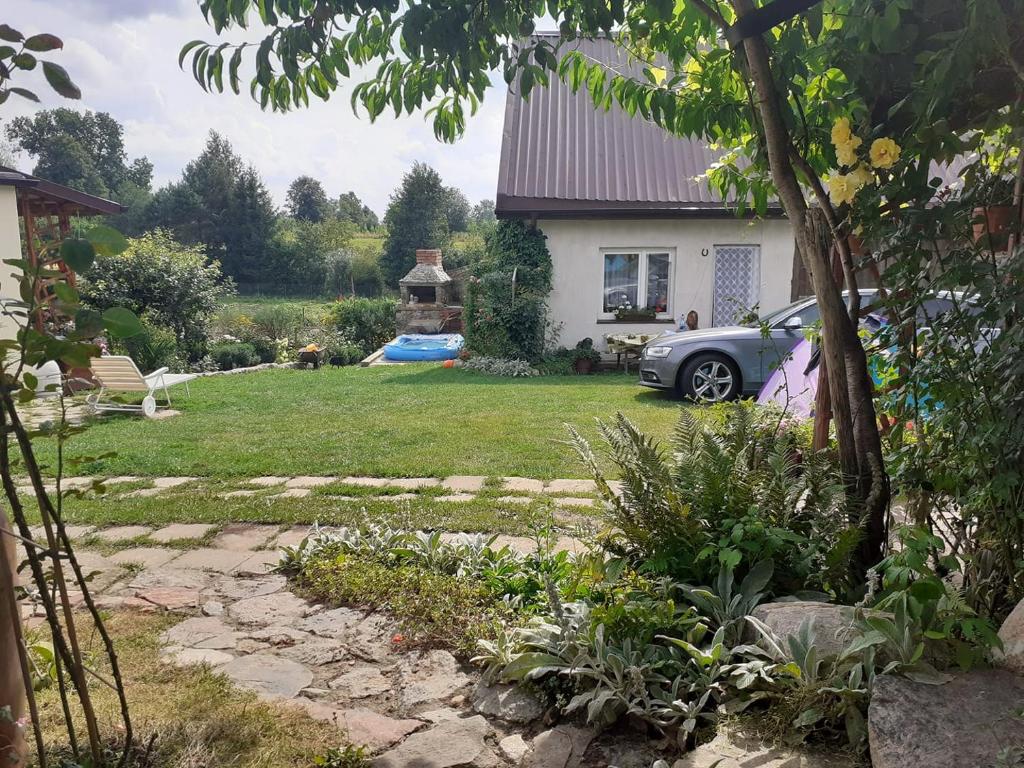 a garden with a car parked in front of a house at Domek na Mazurach Ełk. Rogale in Stare Juchy