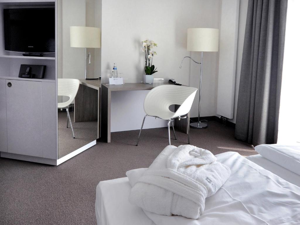 ein Hotelzimmer mit einem Bett mit einem Schreibtisch und Stühlen in der Unterkunft Hotel Schweizer Hof in Kassel