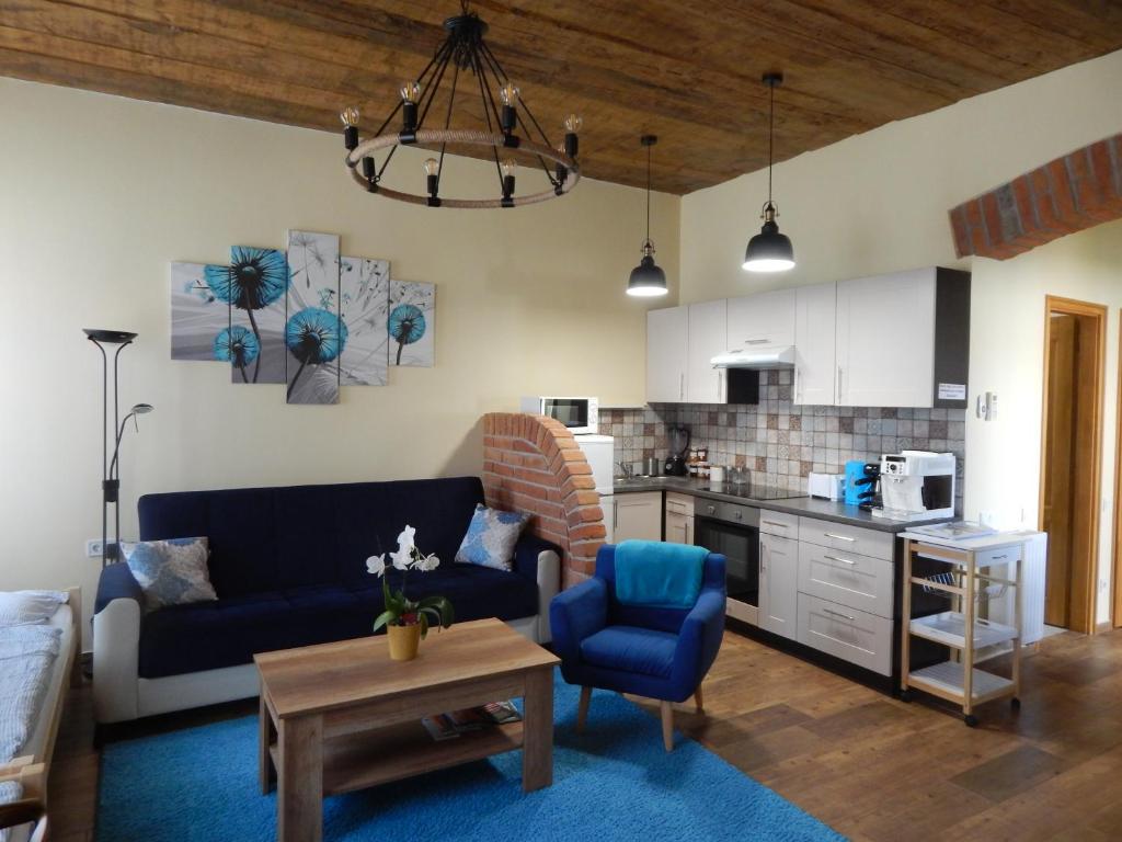 a living room with a blue couch and a kitchen at Boros Vendégház I. in Kőszeg