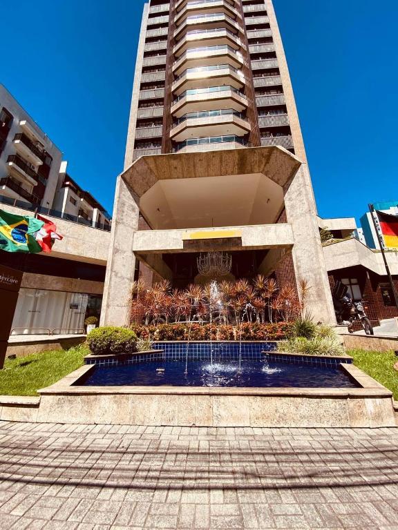 a large building with a fountain in front of it at Apart-hotel, piscina, TV a cabo, academia in Joinville