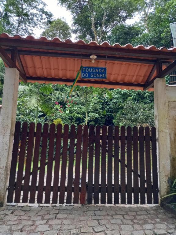 um portão de madeira com um sinal para um parque de cães em CHALÉ POUSADA DO SONHO Guapimirim-RJ em Guapimirim