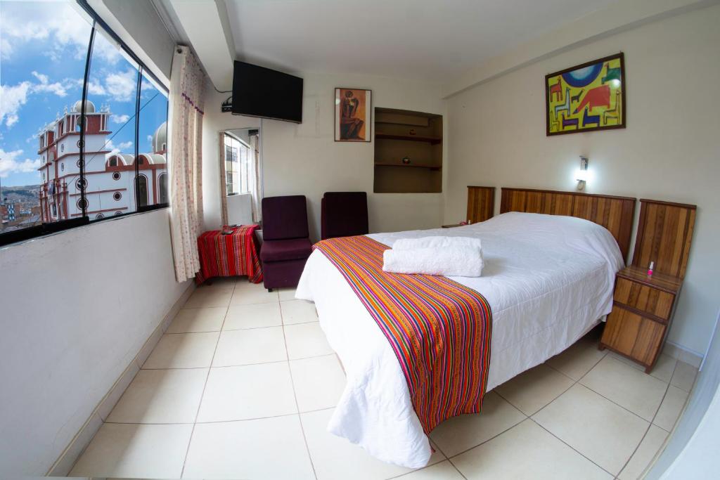 Inka's Rest Hostel في بونو: غرفة فندقية بسرير ونافذة كبيرة