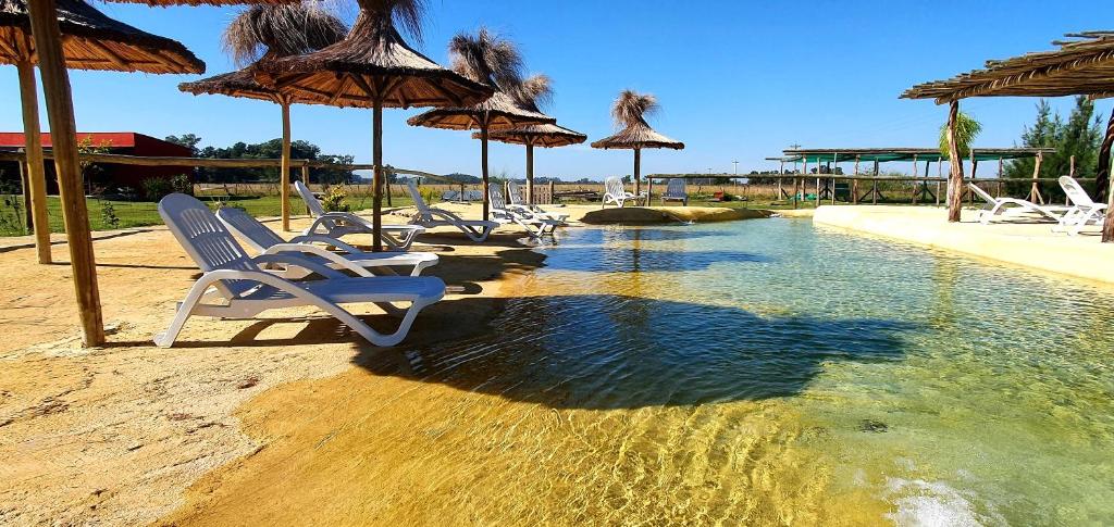 Un grupo de sillas y sombrillas junto a una piscina. en La Maína Uribe Posada, en Uribelarrea