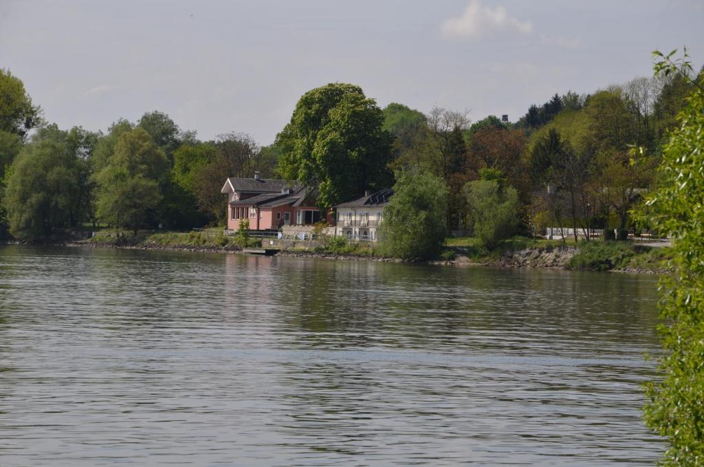 
a house with a boat in the water at Fischwirtshaus Landmotel Die Donaurast in Persenbeug
