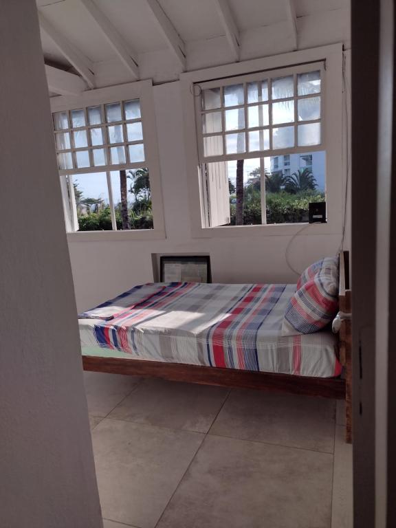 a bed in a room with three windows at Mansão de Pirah Suites in Niterói