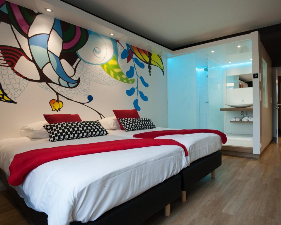 a bedroom with a large bed with a painting on the wall at Appart'hotel Urban Lodge in Chaudfontaine