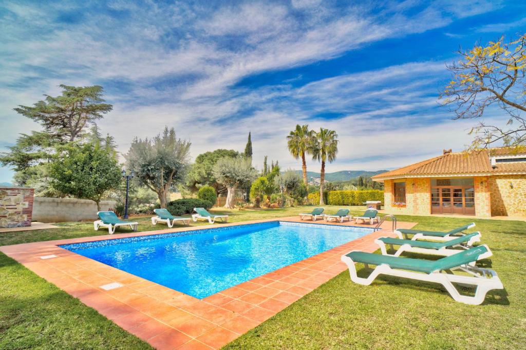a pool with lounge chairs and a house at Villamaresme in Sant Andreu de Llavaneres