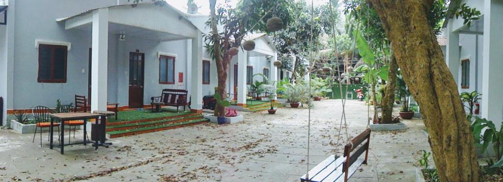 a courtyard of a house with trees and benches at Eden House & Coffee Con Dao in Con Dao