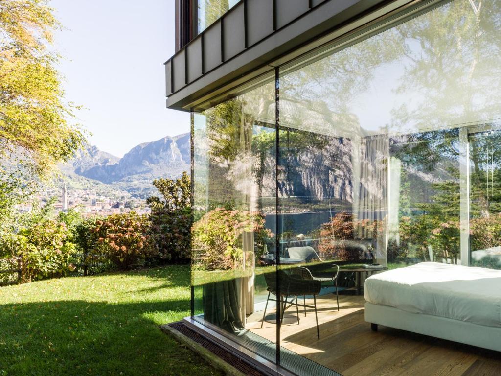 una camera da letto con vista sulle montagne attraverso il vetro di Casa Sull'Albero a Malgrate