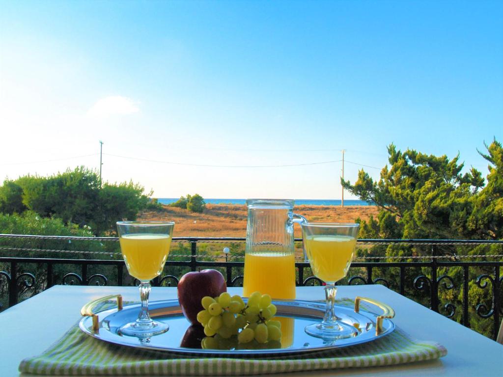 a table with two glasses of orange juice and grapes at Lazaris Apartments in Agios Ioannis Lefkada in Lefkada