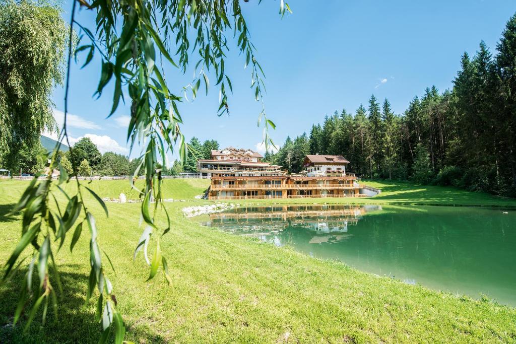 ein Gebäude an der Seite eines Sees in der Unterkunft Hotel Weiher Green Lake in Pfalzen