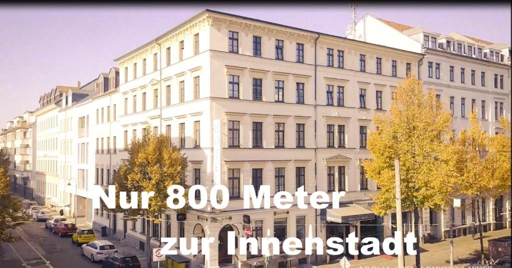 - un grand bâtiment blanc dans une rue de la ville dans l'établissement Hotel Arena City, à Leipzig