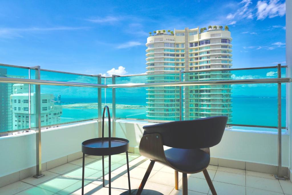 a balcony with two chairs and a view of the ocean at Gurney Drive Mansion One Serviced Apartment in George Town