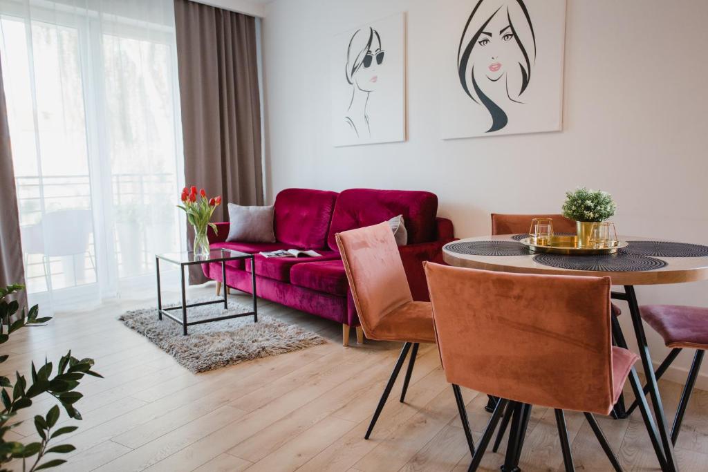 sala de estar con sofá púrpura y mesa en W&K Apartments White&Grey, en Koszalin