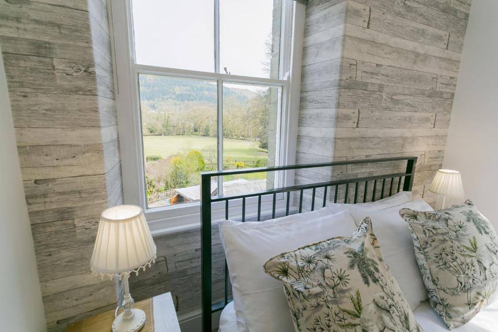 a bedroom with a window and a bed with pillows at Bryn Afon in Betws-y-coed