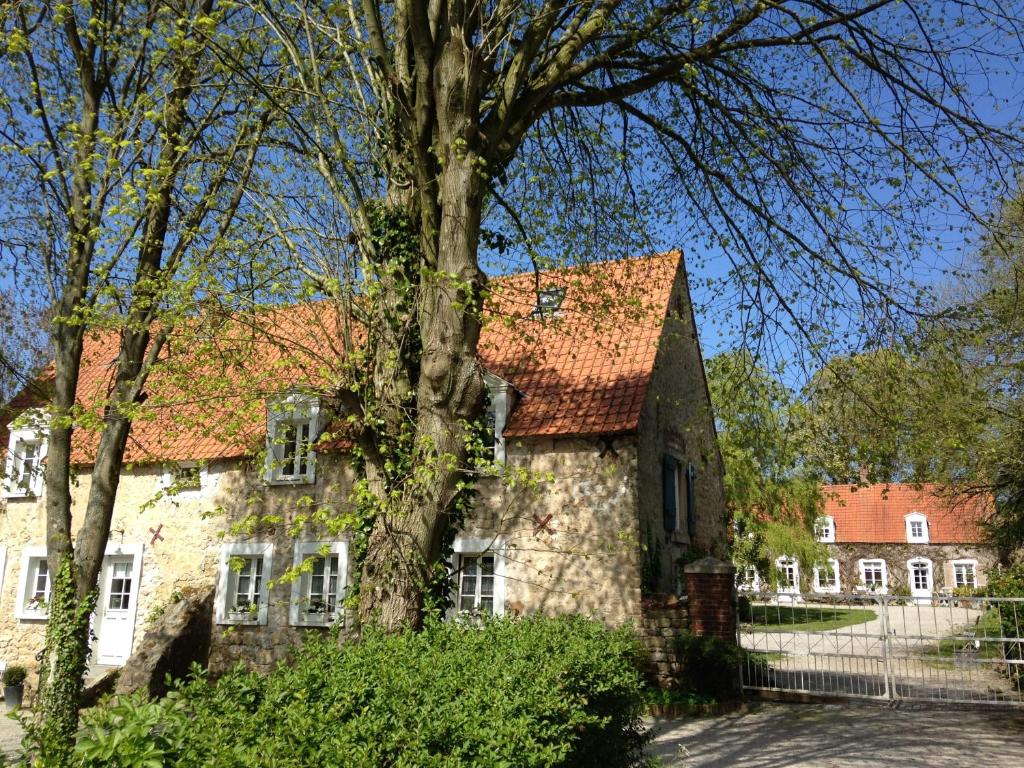 Leubringhen的住宿－迪日卡農場旅館，一座古老的石头房子,前面有一棵树
