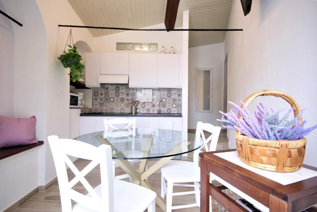 a dining room with a glass table and white chairs at Casa di Luigi ed Ernestina in Dolcedo