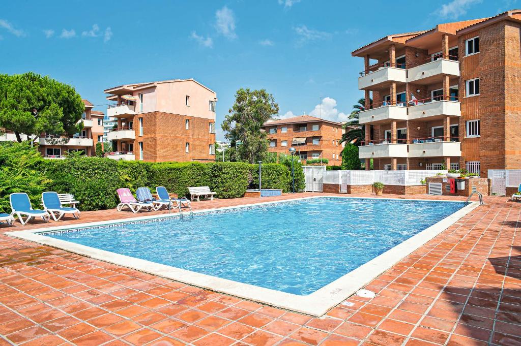 uma piscina com duas cadeiras e um edifício em Pierre & Vacances Comarruga em Comarruga