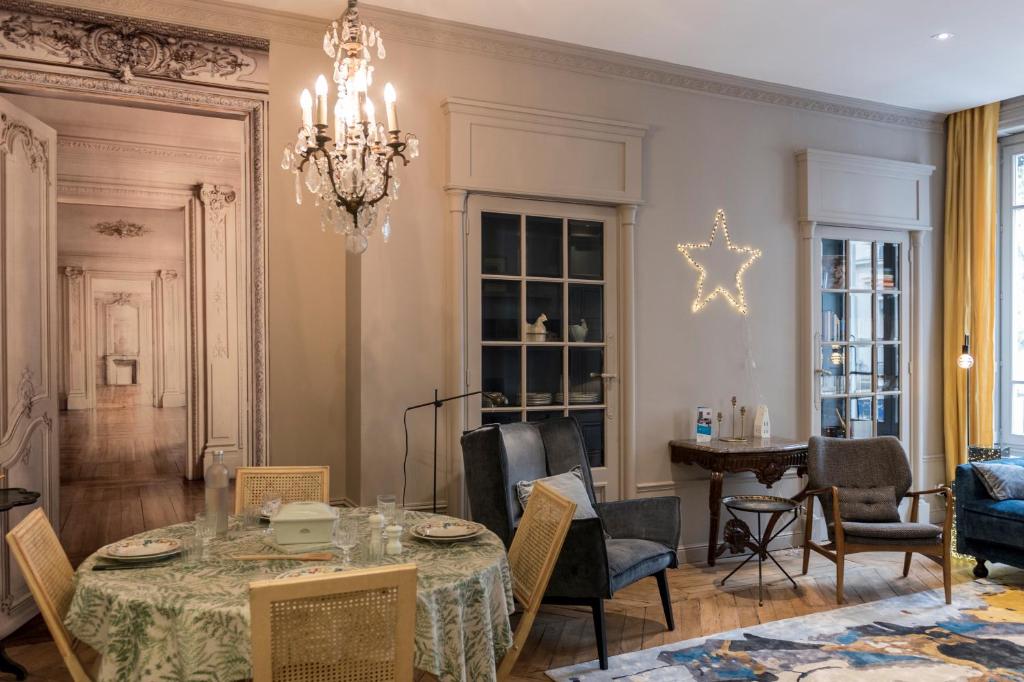 une salle à manger avec une table, des chaises et un lustre dans l'établissement ELLA - Magnifique appartement, à Lyon