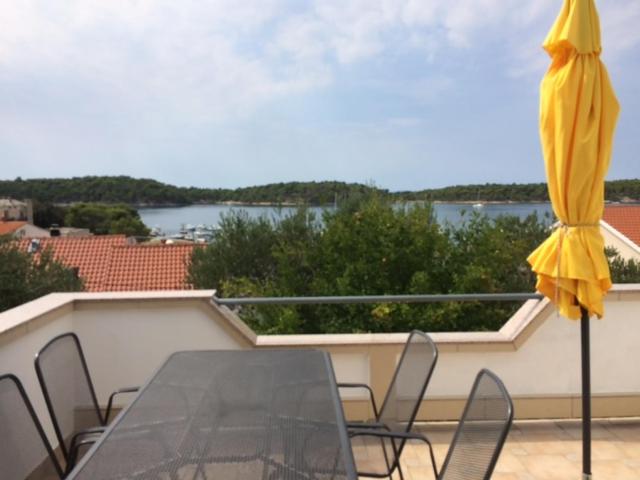 een tafel en stoelen op een balkon met een gele parasol bij APARTMAN I SOBE MARIJANA in Rab
